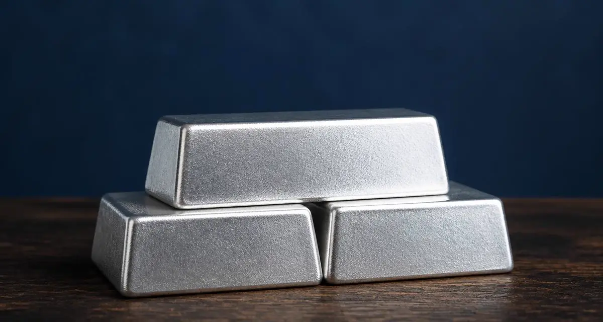 Drie blanco zilverbaren gestapeld op donker hout tegen een marineblauwe achtergrond